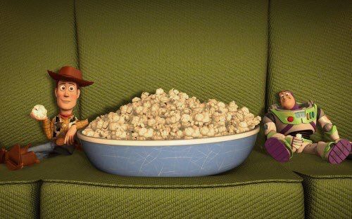 Animated scene inspired by “Toy Story” showing a huge bowl of popcorn on a green couch, with Woody sitting on one side holding a piece of popcorn and Buzz Lightyear lounging on the other side.